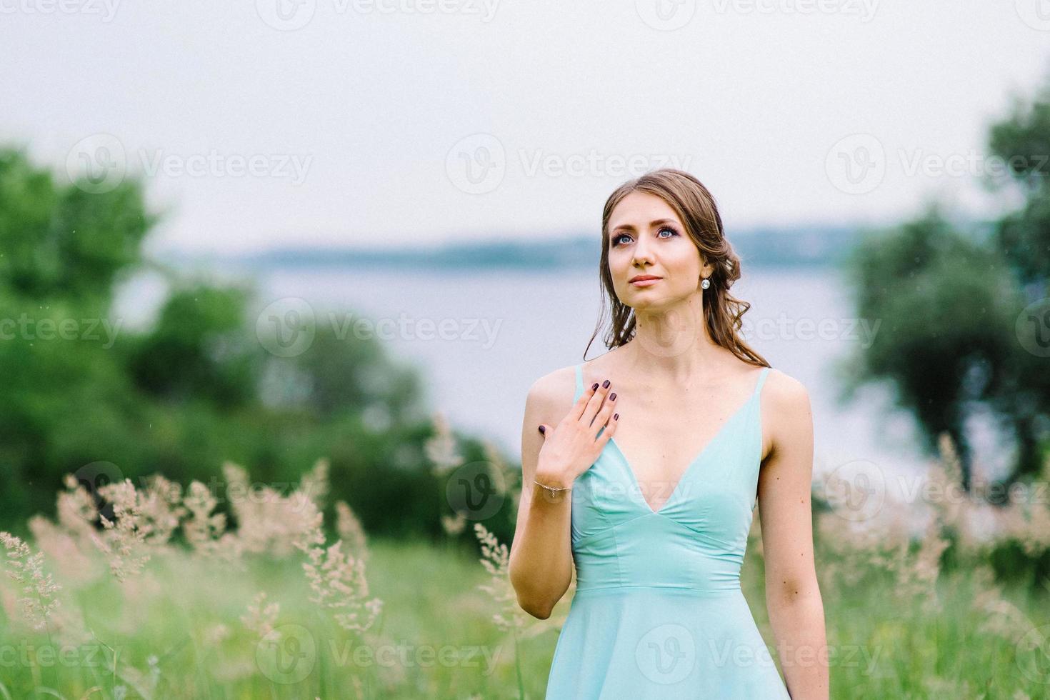 gelukkig meisje in een turquoise lange jurk in een groen park foto