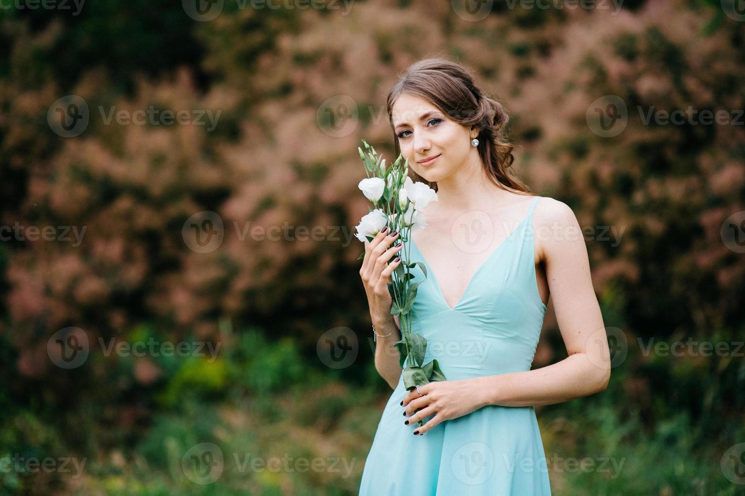 gelukkig meisje in een turquoise lange jurk in een groen park foto