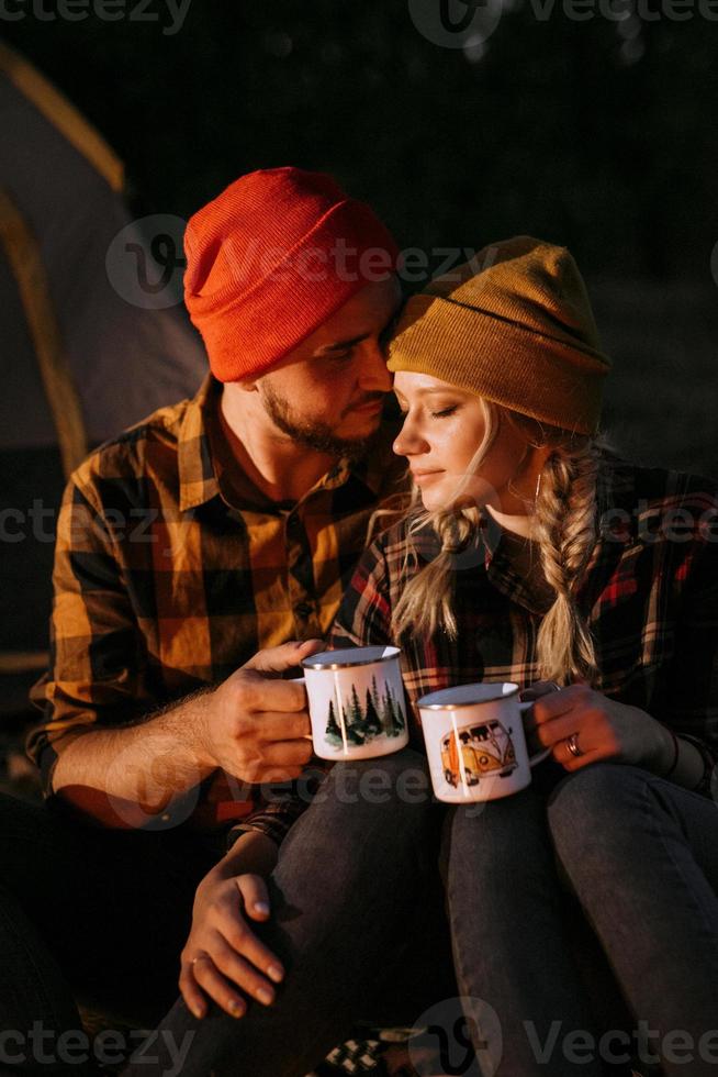 jong stel een jongen en een meisje met fleurige gebreide mutsen stopten op een camping foto