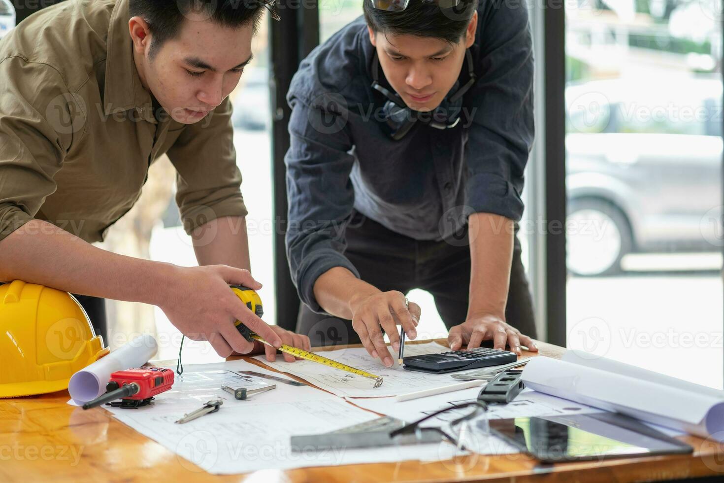 Aziatisch ingenieurs brainstorm en meten naar document kosten schattingen en schrijven verdieping plannen voor bouwkundig en bouwkunde ontwerpen voor huizen en gebouwen. foto