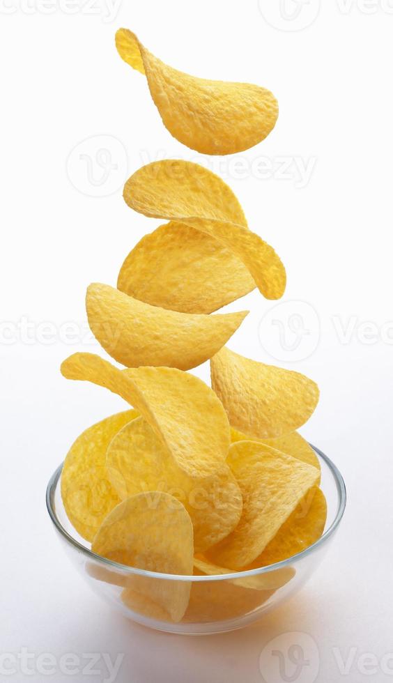 chips vallen in glazen kom geïsoleerd op een witte achtergrond foto