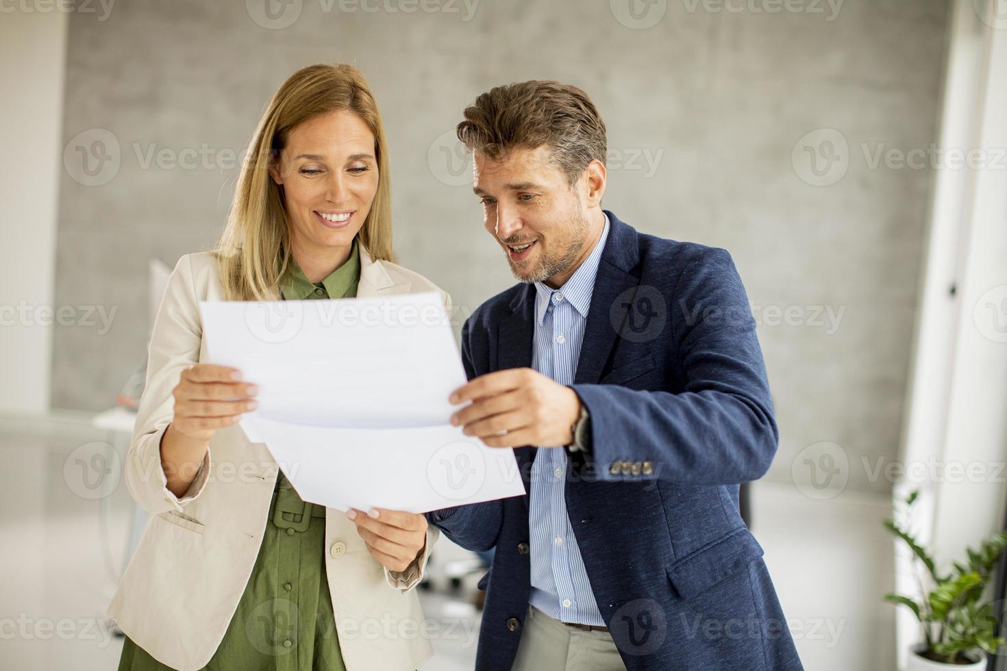 twee professionals glimlachen en kijken naar documenten foto