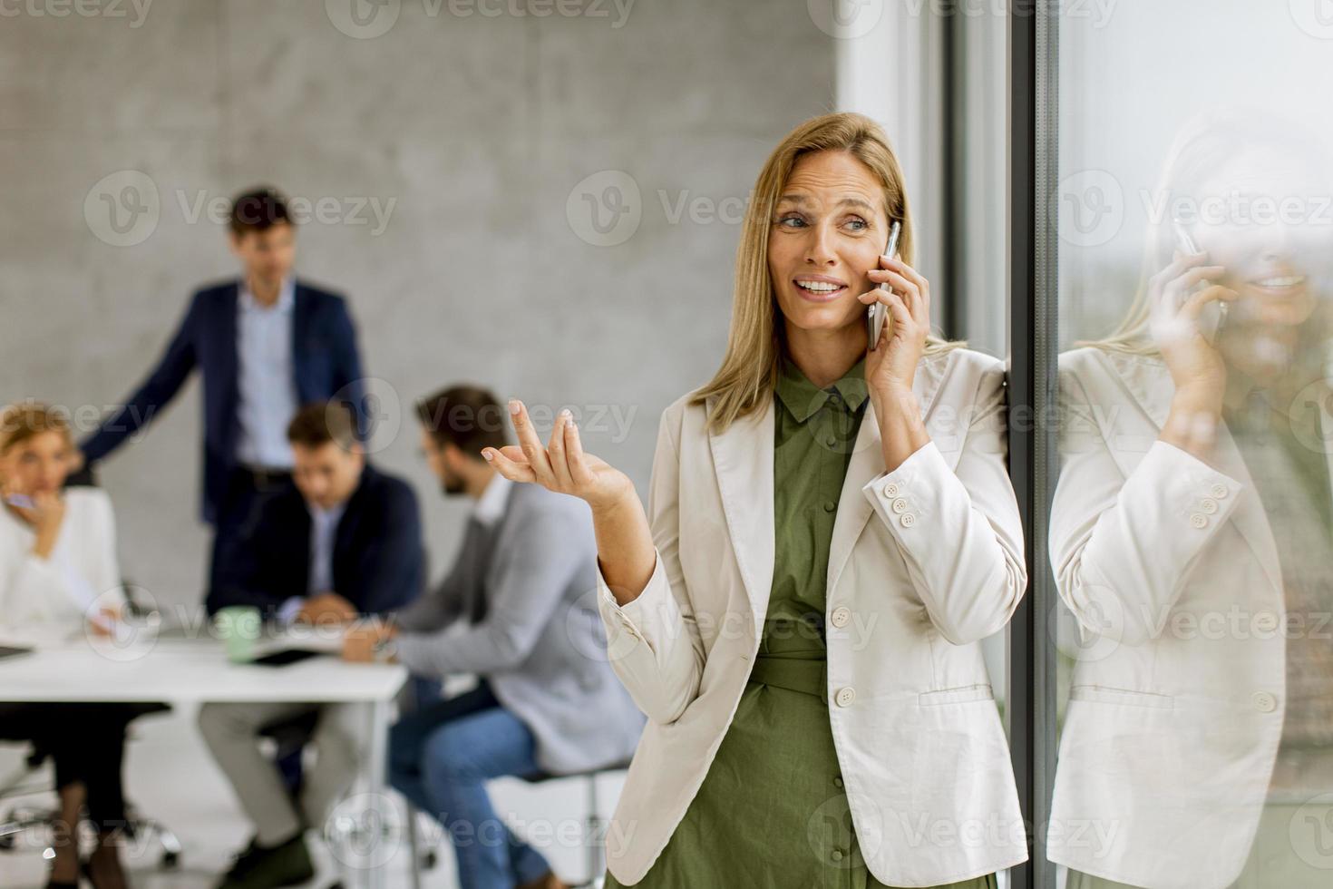 zakenvrouw op telefoon met team op de achtergrond foto