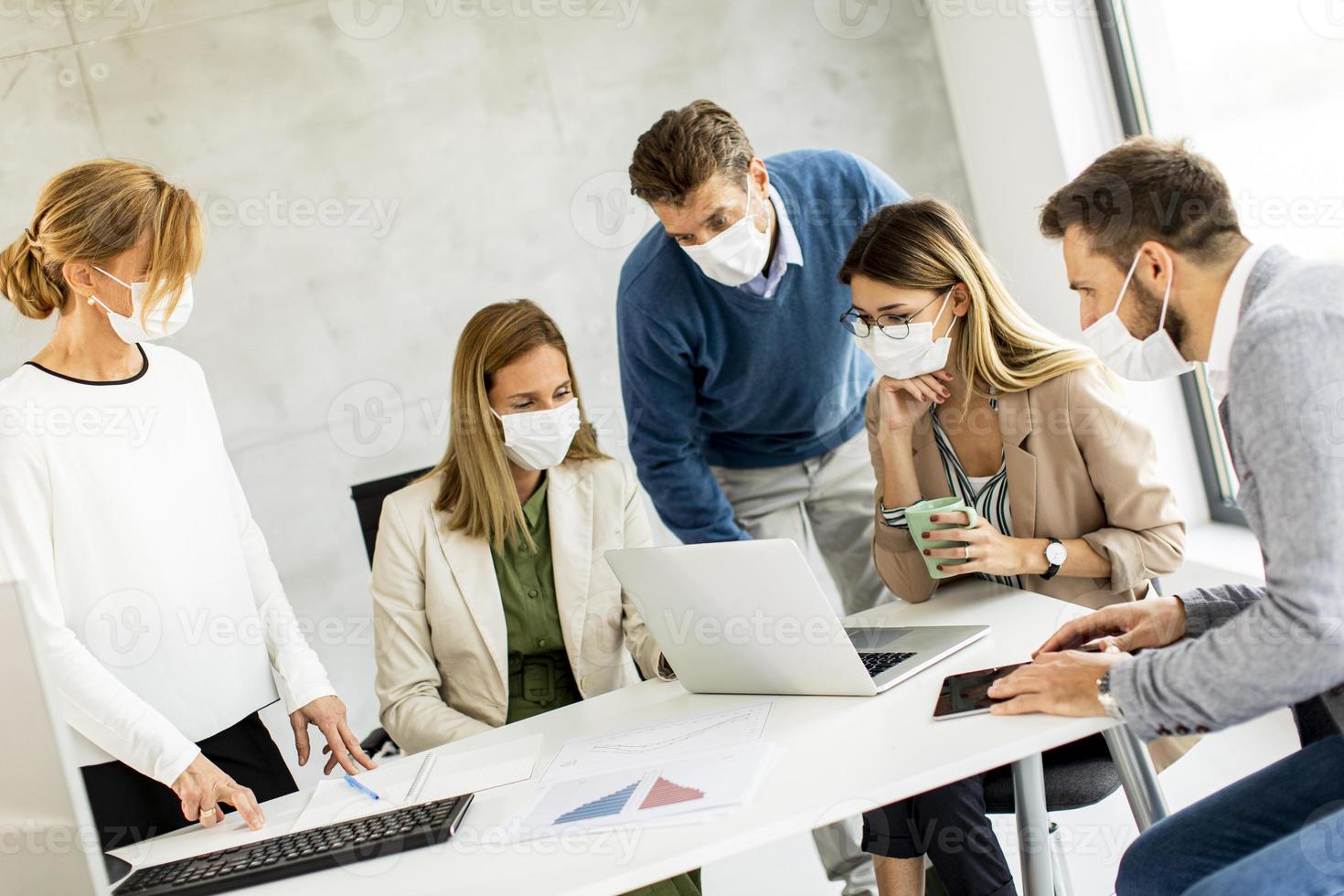 gemaskerd team dat naar een laptop kijkt foto