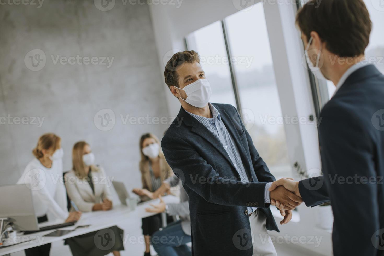 twee gemaskerde zakenlieden die elkaar de hand schudden foto