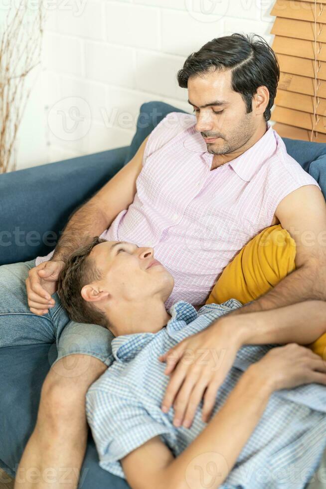 liefhebbend dezelfde seks mannetje paar aan het liegen Aan sofa Bij huis aan het kijken TV en ontspannende samen. homoseksueel verhouding concept. foto