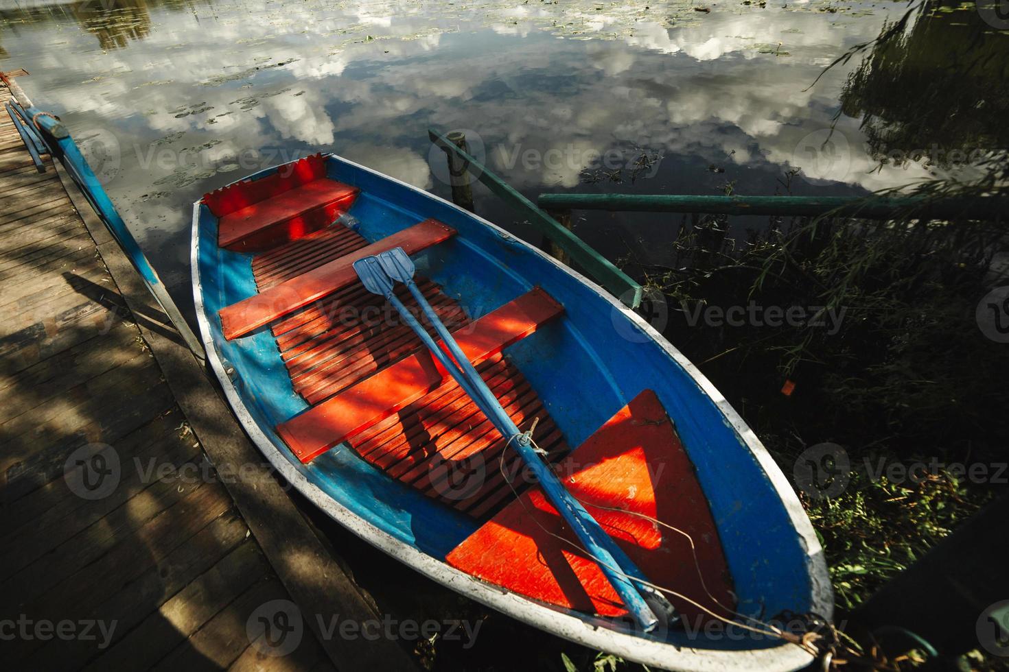 houten kleurrijke boot met roeispanen aan de oever van het meer op een heldere zomerdag foto