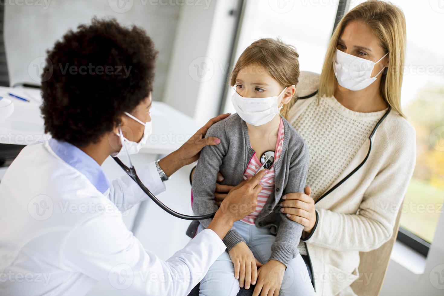 kinderarts luistert naar de longen van het meisje foto