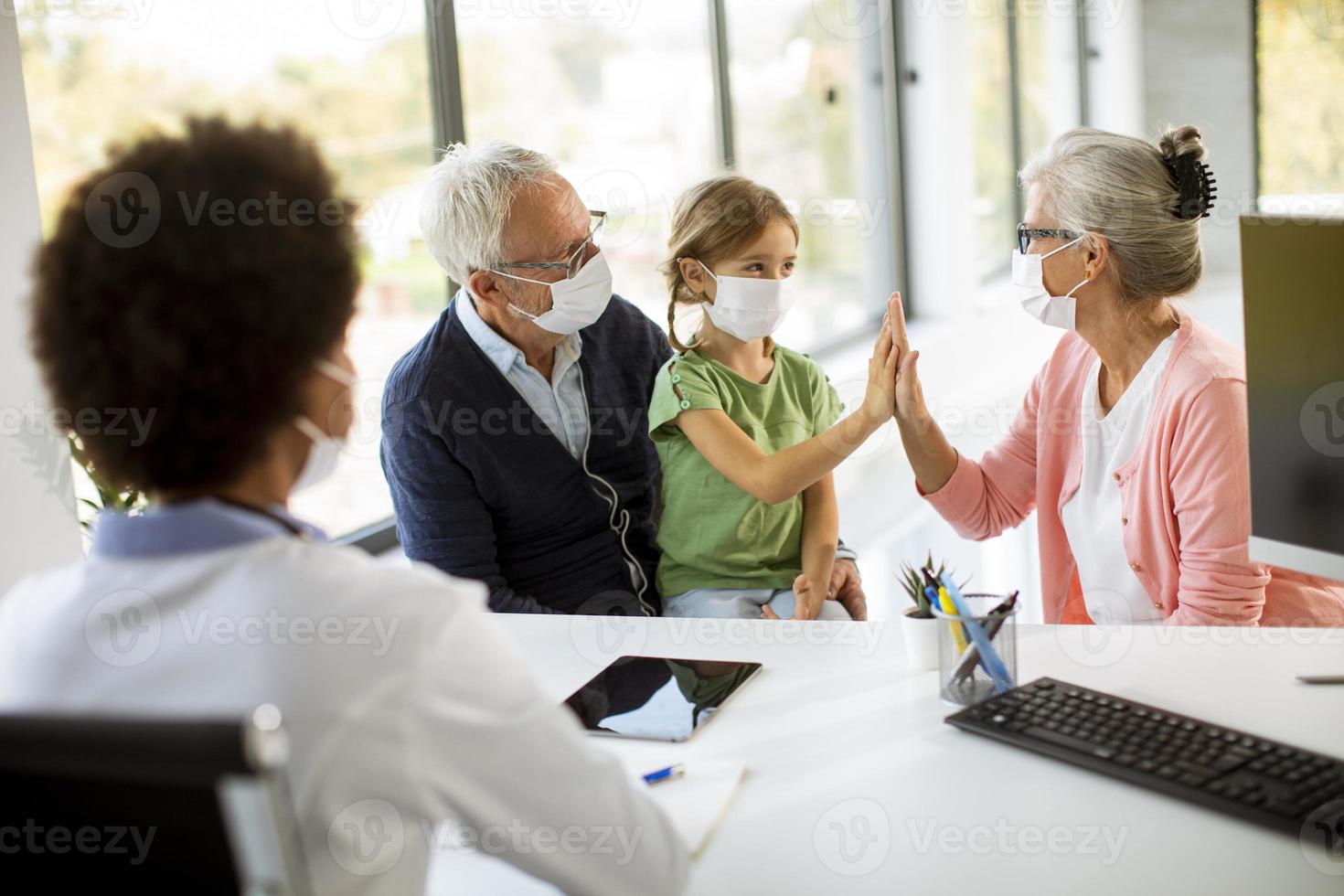 grootouders en kleindochter in maskers bij de dokter foto