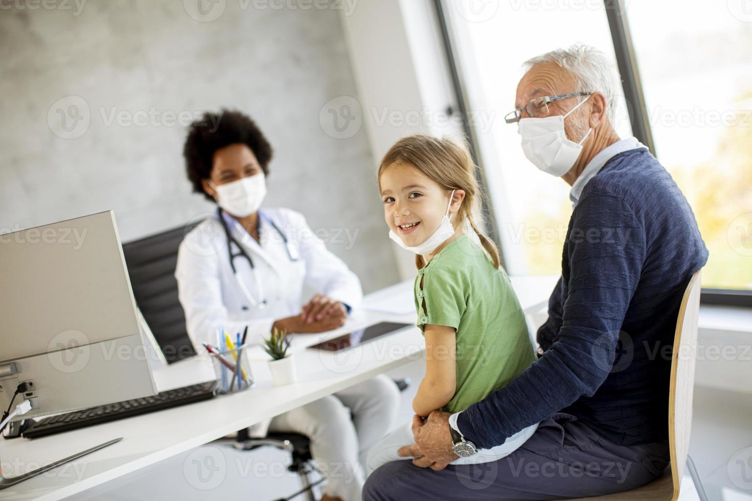 klein meisje met grootvader in het kantoor van de dokter foto