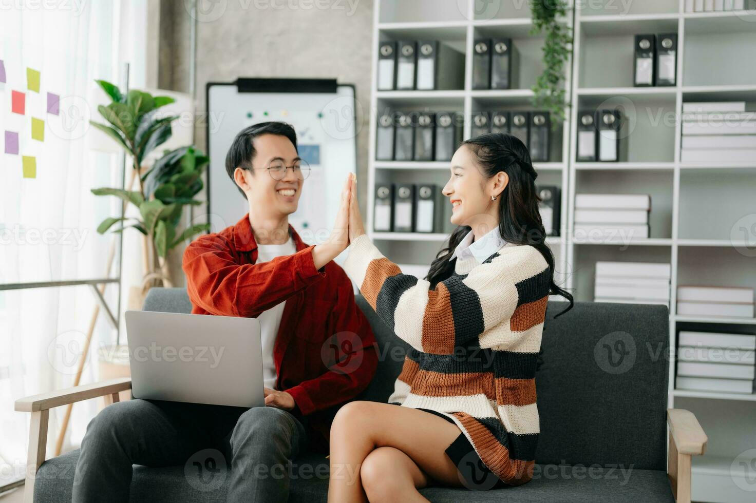 Aziatisch bedrijf team creatief mensen uit het bedrijfsleven collega, samenspel vieren prestatie en in planning ontwerp in creatief Aan sofa foto
