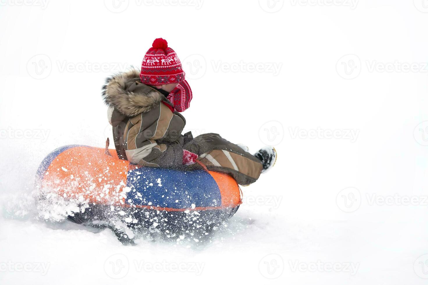 kind in winter. vrolijk jongen is rijden een opblaasbaar slee. foto