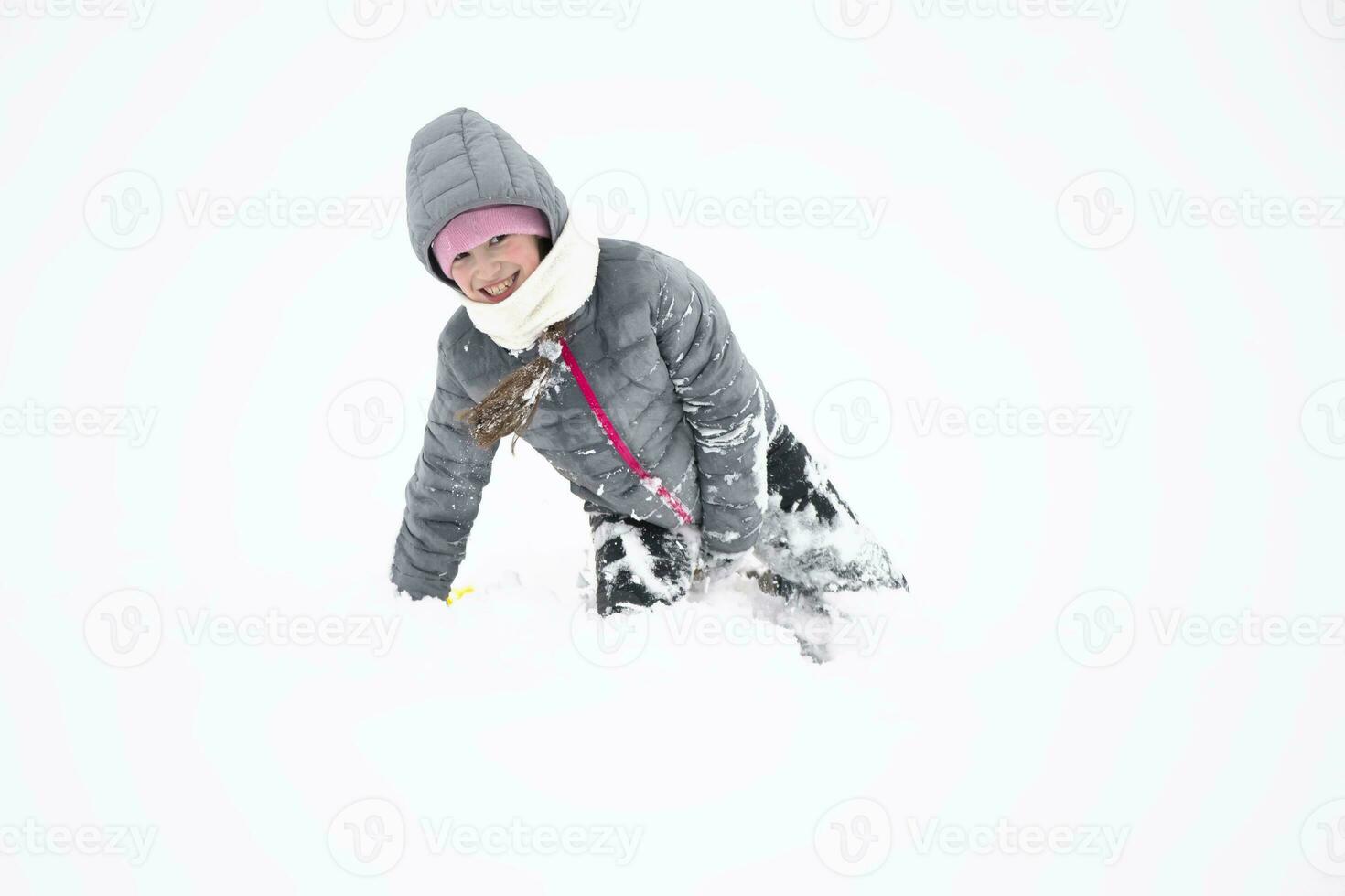 kind in winter. vrolijk weinig meisje in warm kleren in de sneeuw. foto