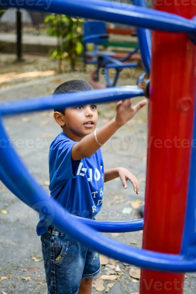 Aziatisch jongen aan het doen routine- oefening in maatschappij park gedurende de ochtend- tijd. schattig weinig kind oefening en Sportschool naar houden zichzelf fit voor leven. kind oefening buitenshuis schieten foto