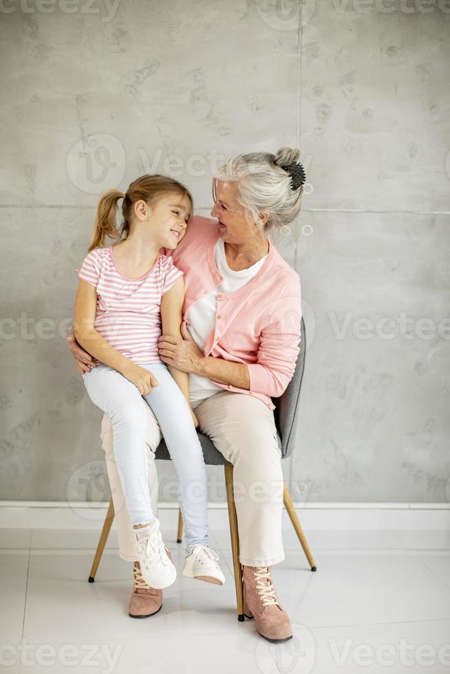 klein meisje met haar grootmoeder zittend in een stoel foto