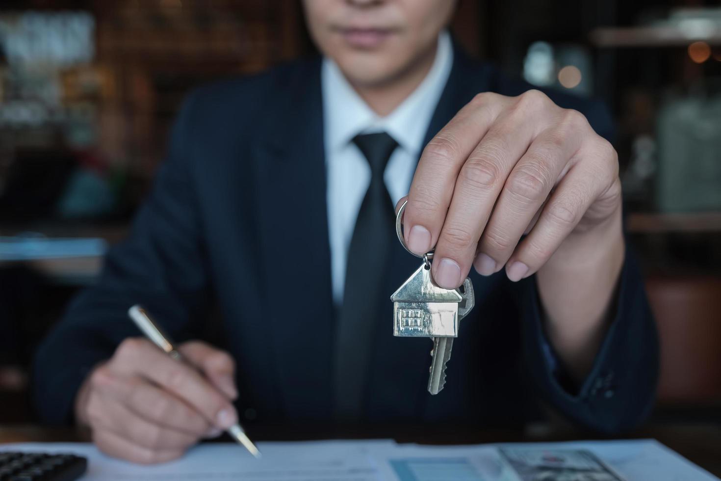 bankmedewerker geeft sleutelhuis aan klant na het maken van een huiskoopcontract foto