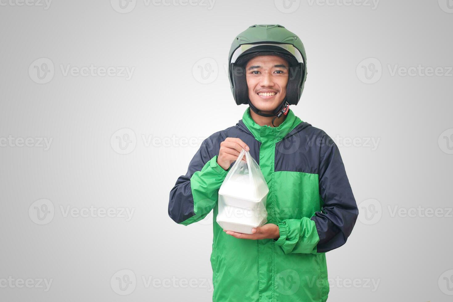 portret van Aziatisch online taxi bestuurder vervelend groen jasje en helm Holding voedsel verpakt in schuim plastic doos. geïsoleerd beeld Aan wit achtergrond foto