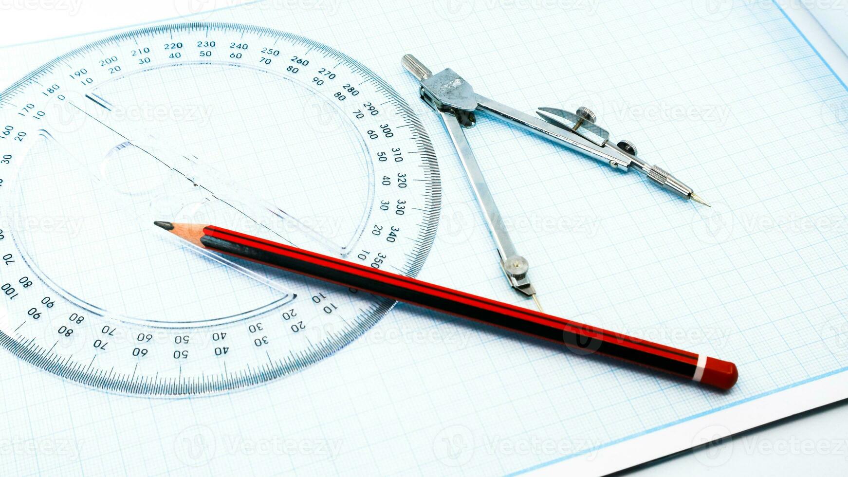 Aan blauw diagram papier zijn kompassen, gradenboog, heerser, en een potlood foto