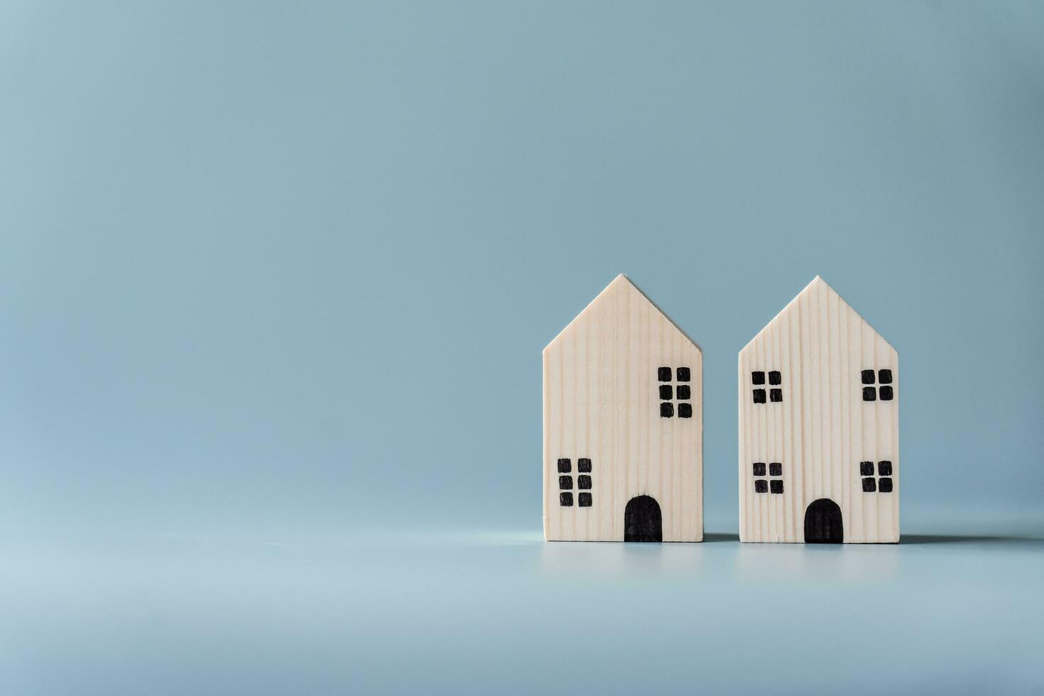 klein houten huis Aan licht blauw achtergrond voor echt landgoed en woon- gebouw concept. weinig huis model- met kopiëren ruimte. foto