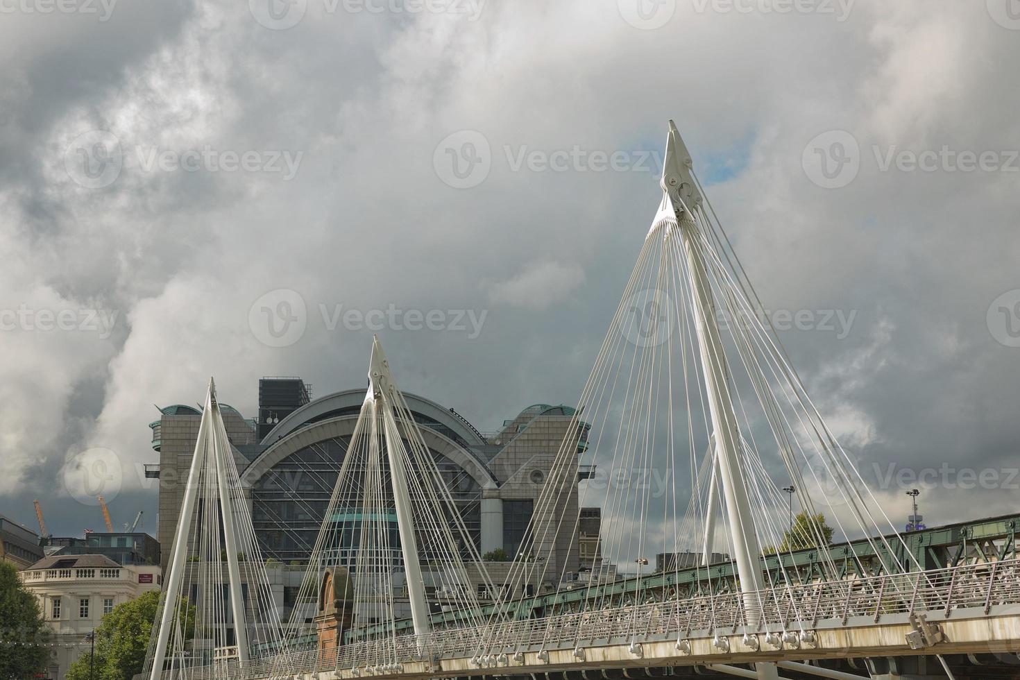 uitzicht op de gouden jubileumbruggen en het Charing Cross-station vanaf de zuidkust van de rivier de Theems in Londen op een bewolkte zomerdag foto