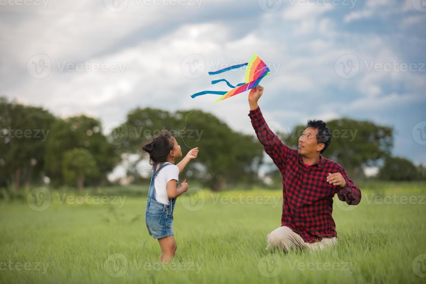 kind en vader spelen met vlieger in het park foto