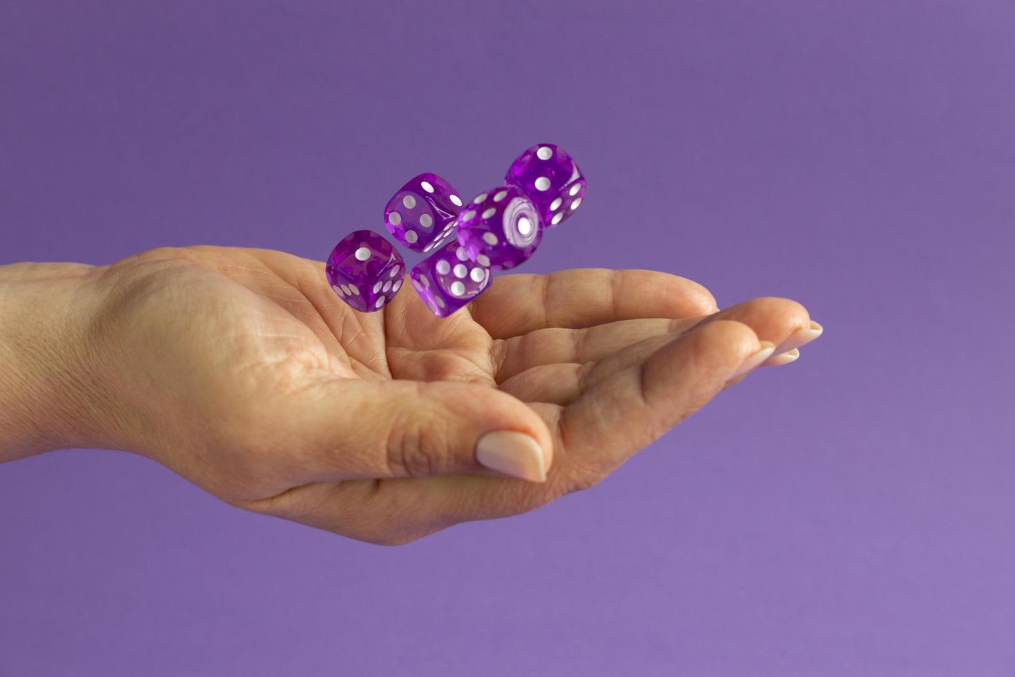 handen met dobbelstenen op paarse achtergrond foto