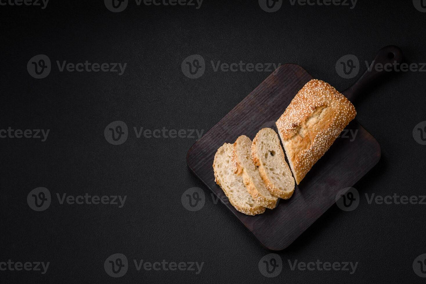 krokant tarwe meel baguette met sesam zaden Aan een houten snijdend bord foto