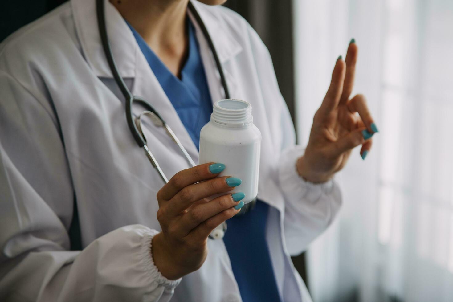 echt vrouw dokter gebruik makend van laptop en schrijven aantekeningen in medisch logboek zittend Bij bureau. jong vrouw professioneel medisch arts vervelend wit jas en stethoscoop werken Aan computer Bij werkplek. foto