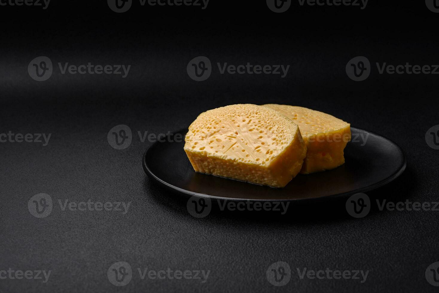 heerlijk poreus geel kaas besnoeiing in groot stukken Aan een keramisch bord foto