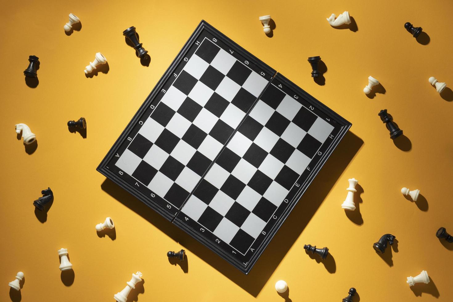 schaakstukken en schaakbord op gele achtergrond foto