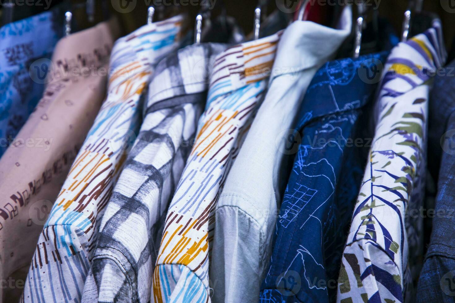 kleurrijk verscheidenheid van overhemden ophangingen in een kleding toonzaal. opsluiten focus foto