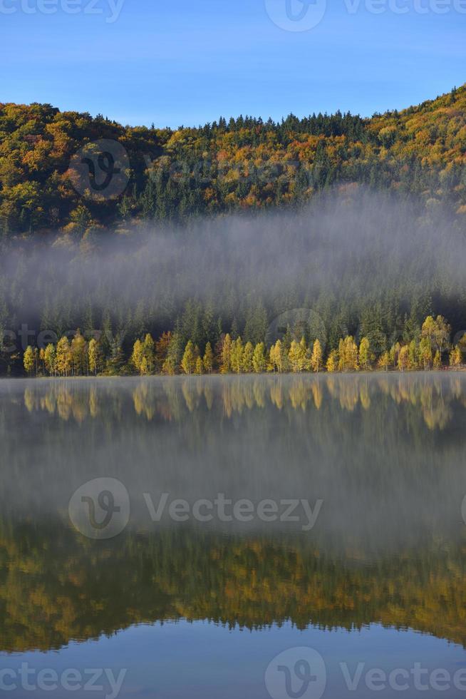 herfst landschap in de bergen met bomen weerspiegelen in het water bij st ana lake roemenië foto