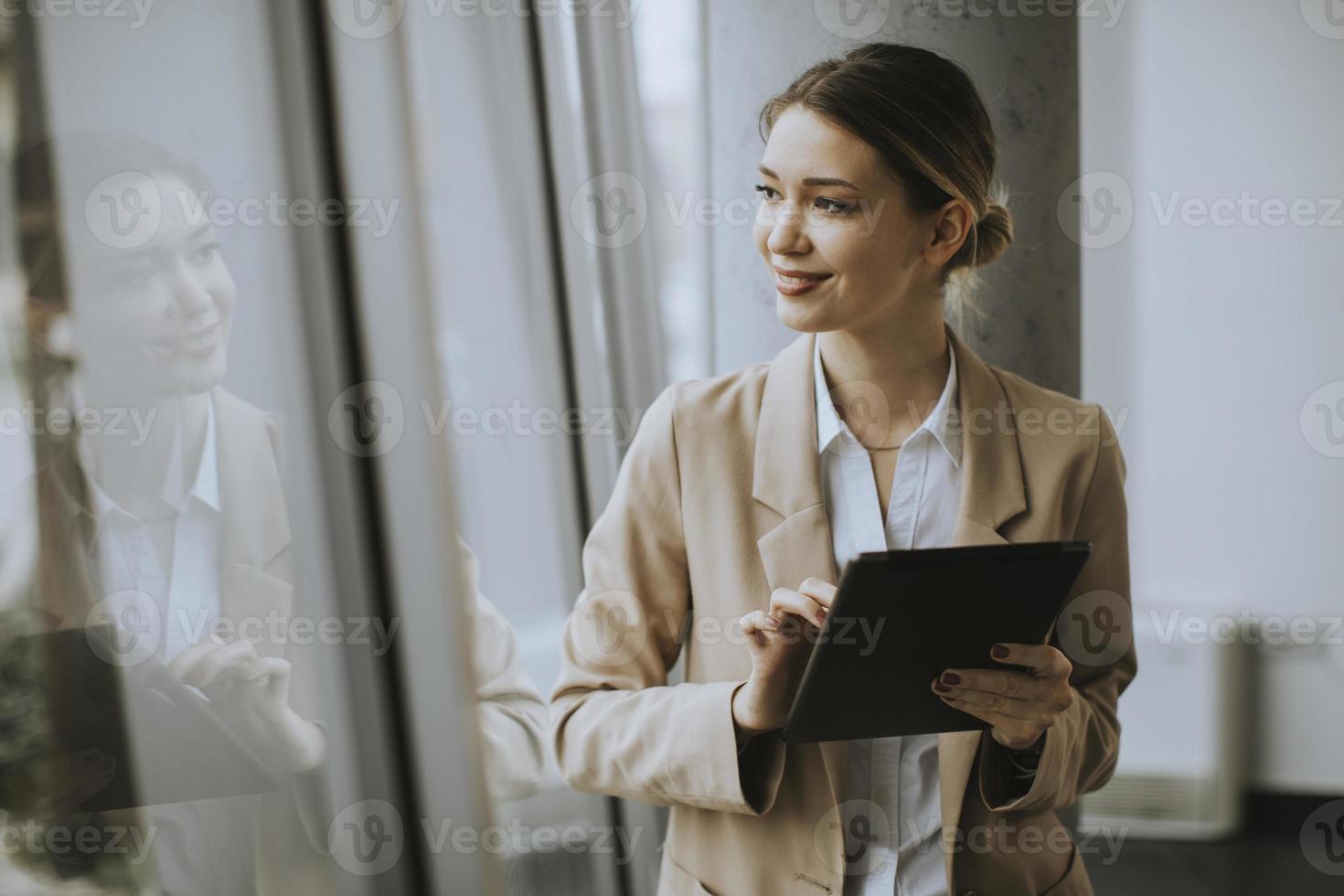 vrouw kijkt uit raam en met behulp van tablet foto