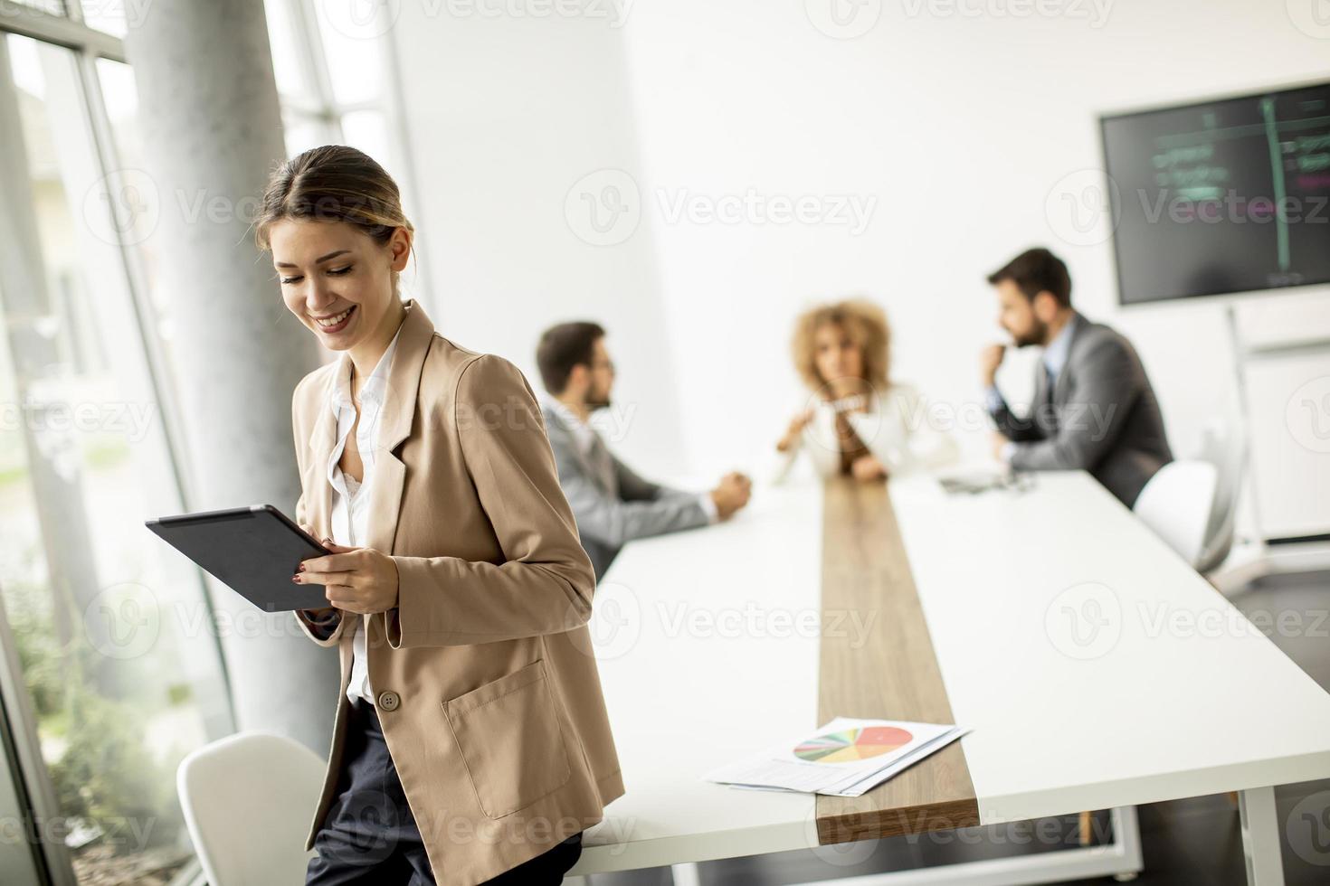 zakenvrouw met behulp van tablet met een bijeenkomst op de achtergrond foto