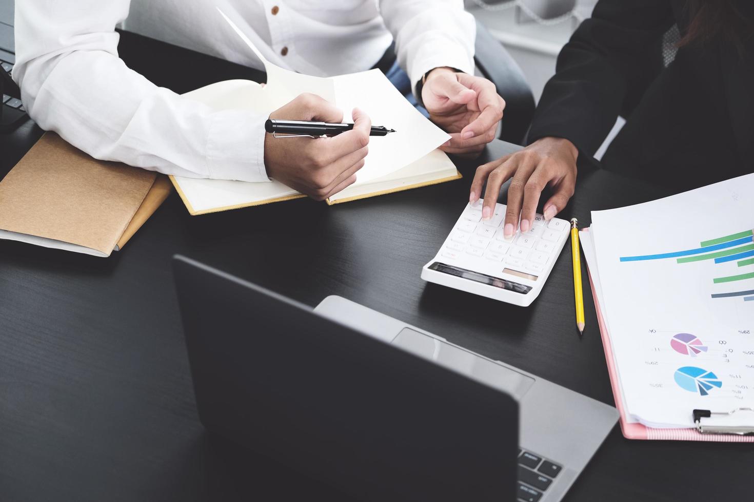 twee jonge bedrijfsleiders bespreken om hun bedrijfsconcept te veranderen om de winst en de kracht van hun bedrijf te vergroten door rekenmachine en laptop voor werk te gebruiken. foto