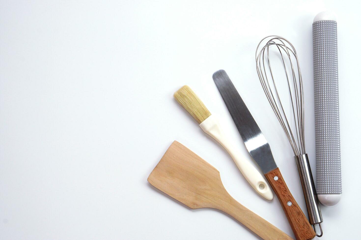 top visie keukengerei houten rollend pin, houten spatel en ei klopper Aan wit achtergrond. materialen of keuken uitrusting voor bakkerij. foto