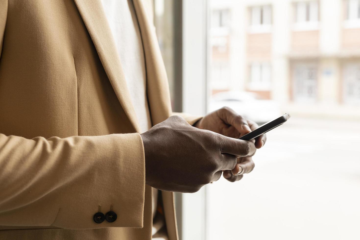 man houdt een telefoon vast met in beige pak foto