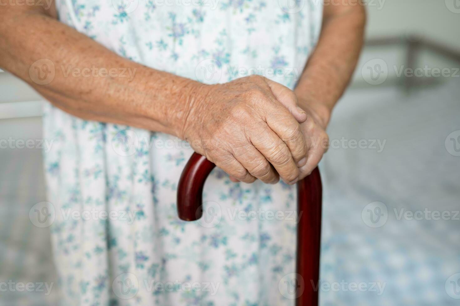 Aziatisch ouderen onbekwaamheid vrouw Holding wandelen stok, hout riet, ronde handvat, wandelen steun voor helpen naar wandelen. foto