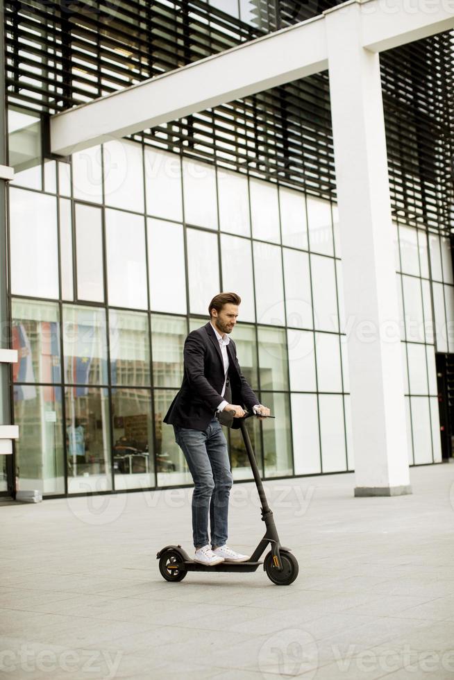 casual zakenman op een scooter voor gebouw foto
