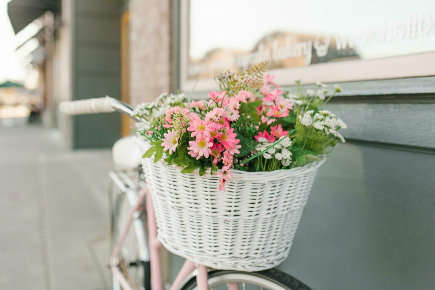 kunstmatig bloemen in de mand van een houten fiets in de buurt de stad cafe foto