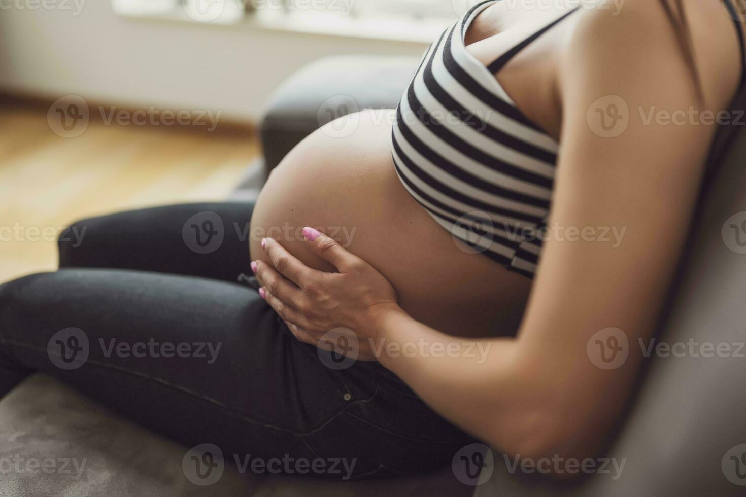 zwanger vrouw ontspannende Bij huis. ze is zittend Aan bed in slaapkamer. foto