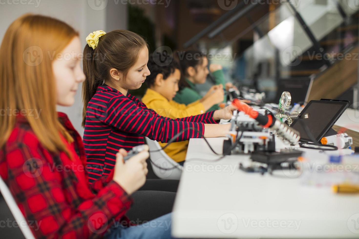 gelukkige jonge geitjes die elektrisch speelgoed en robots programmeren in het klaslokaal van robotica foto
