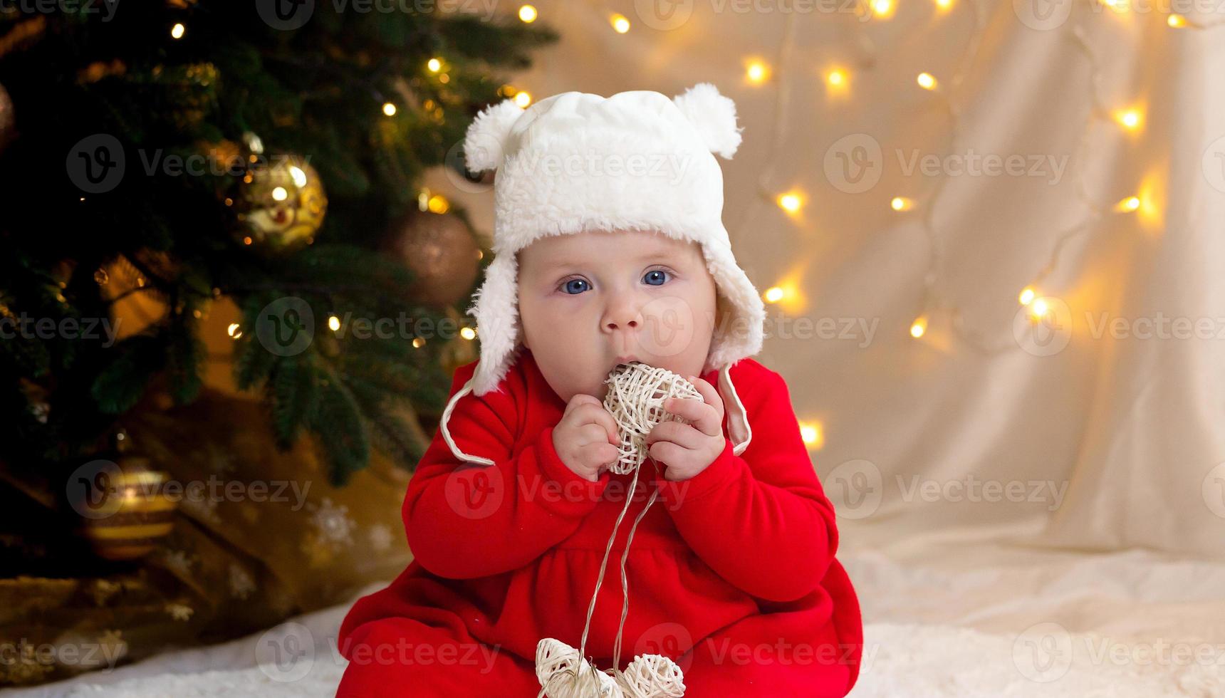 kerstkind dat naar de camera kijkt en een krans met hartjes vasthoudt foto