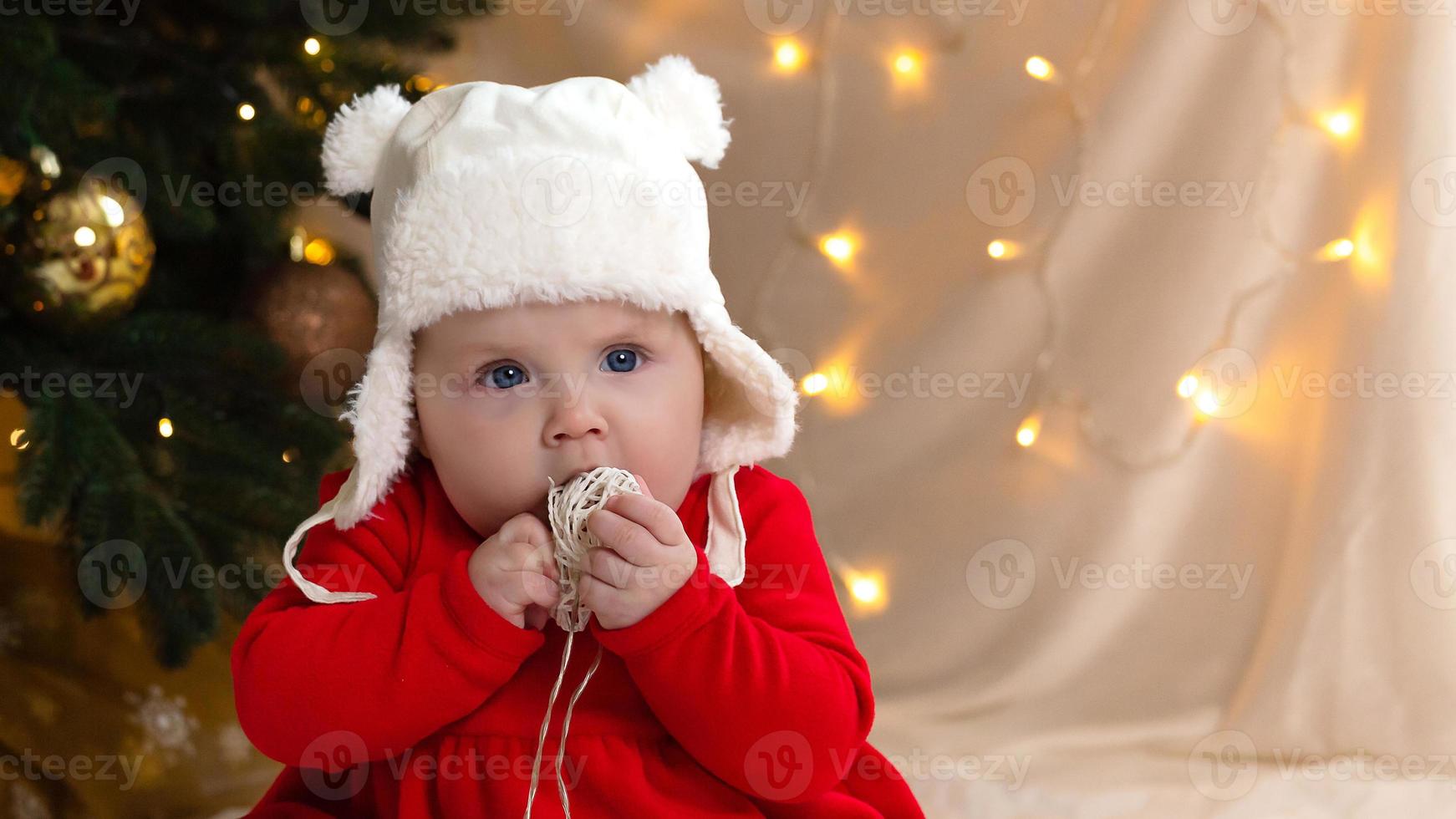 kerstkind dat naar de camera kijkt en een krans met hartjes vasthoudt foto