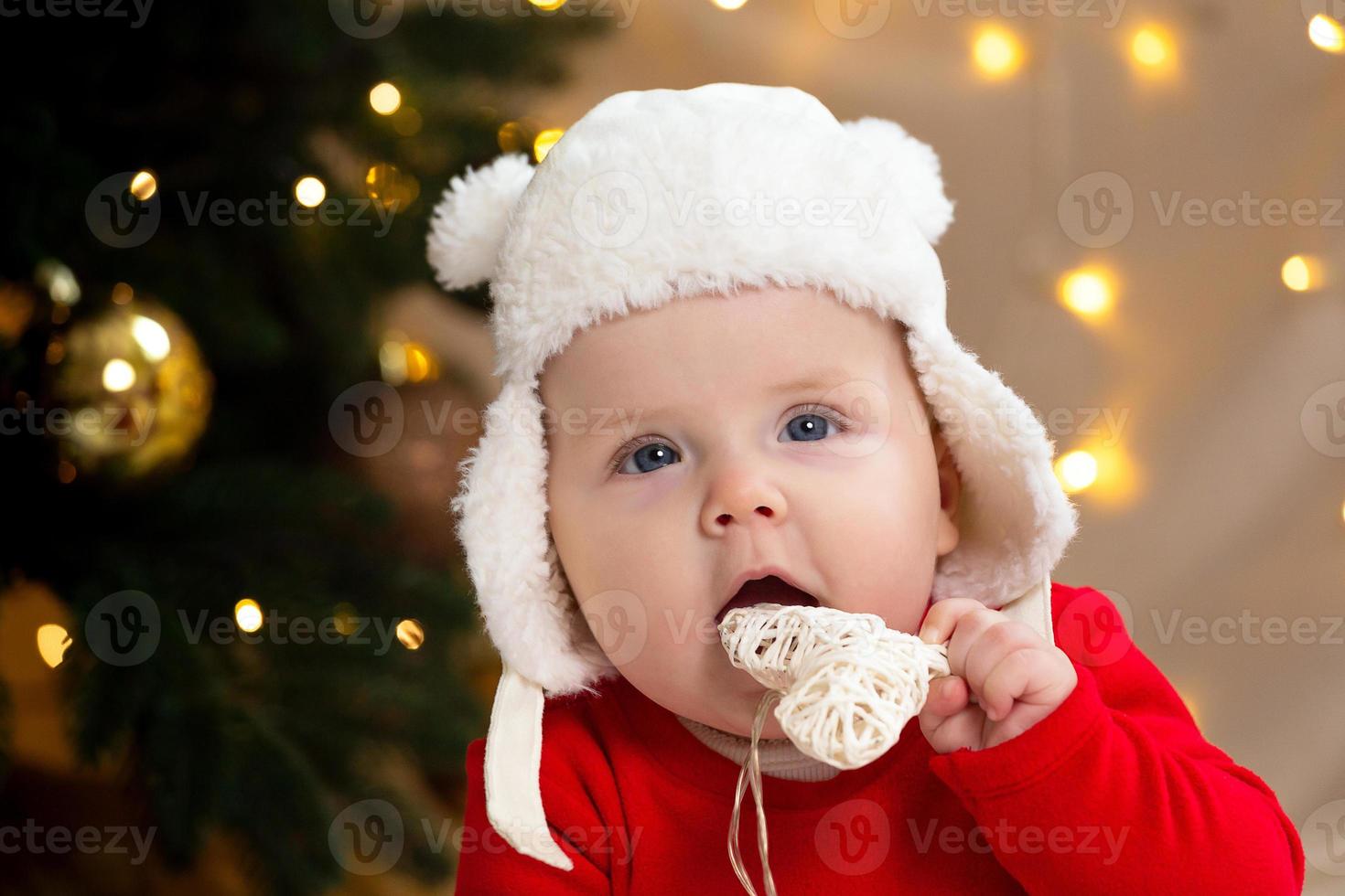 kerstkind dat naar de camera kijkt en een krans met hartjes vasthoudt foto