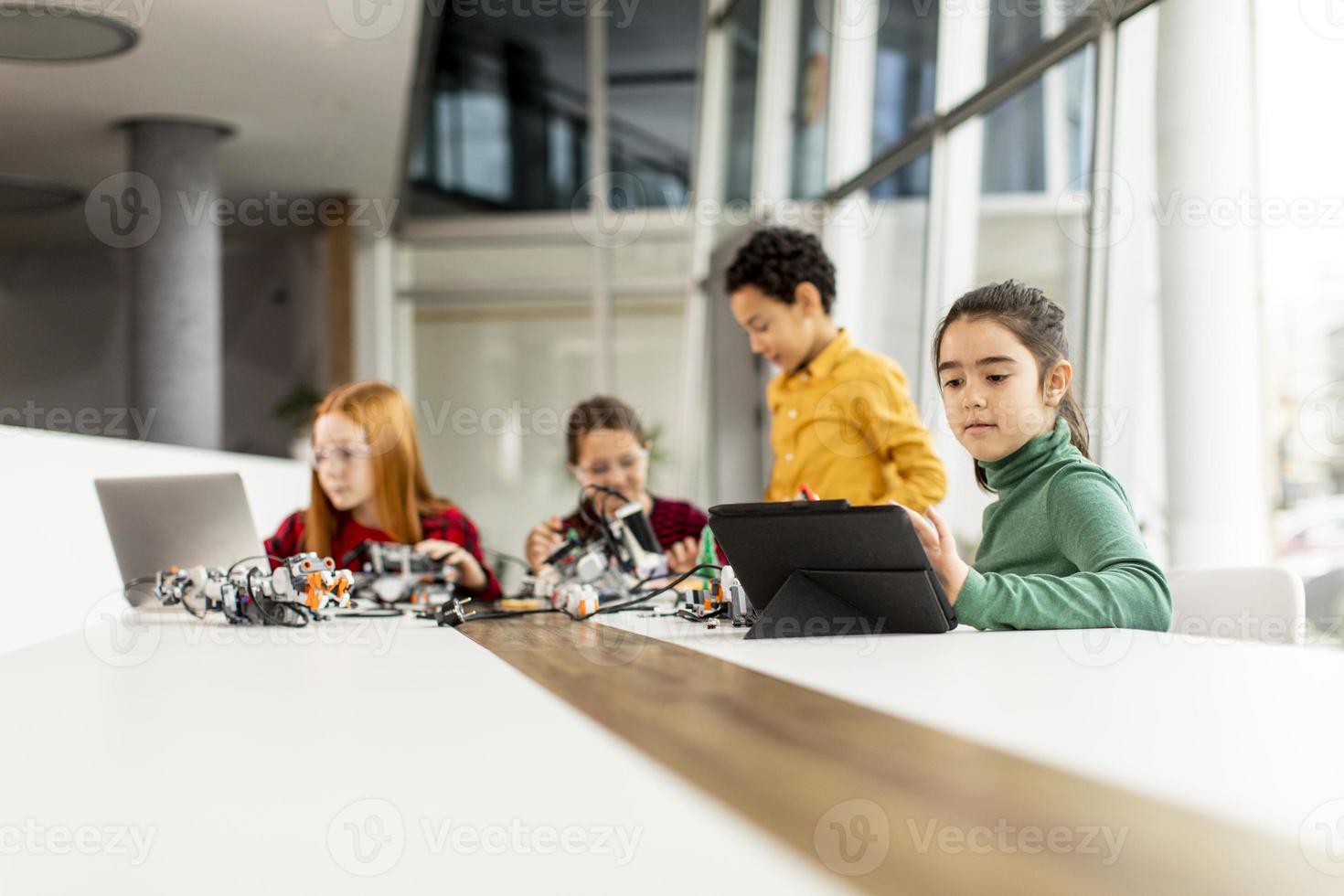 gelukkige jonge geitjes die elektrisch speelgoed en robots programmeren in het klaslokaal van robotica foto