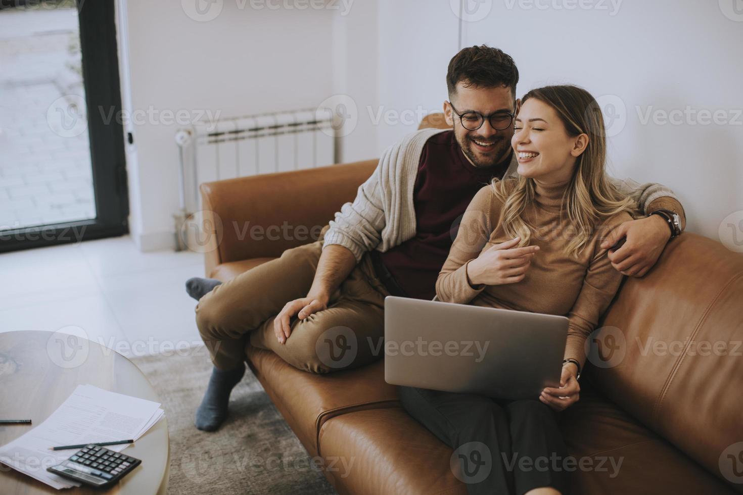 jong koppel samen met behulp van laptop zittend op de bank thuis foto