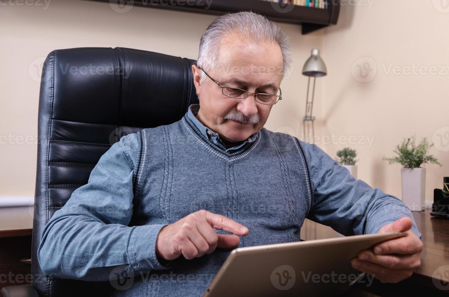 senior man leest nieuws op digitale tablet foto