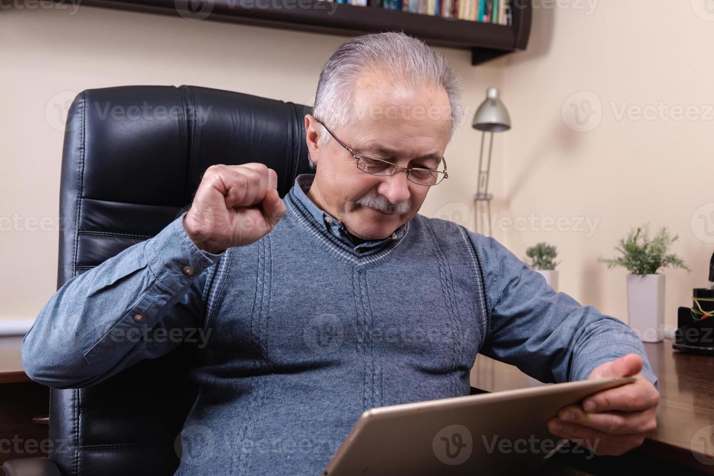 senior man leest nieuws op digitale tablet foto