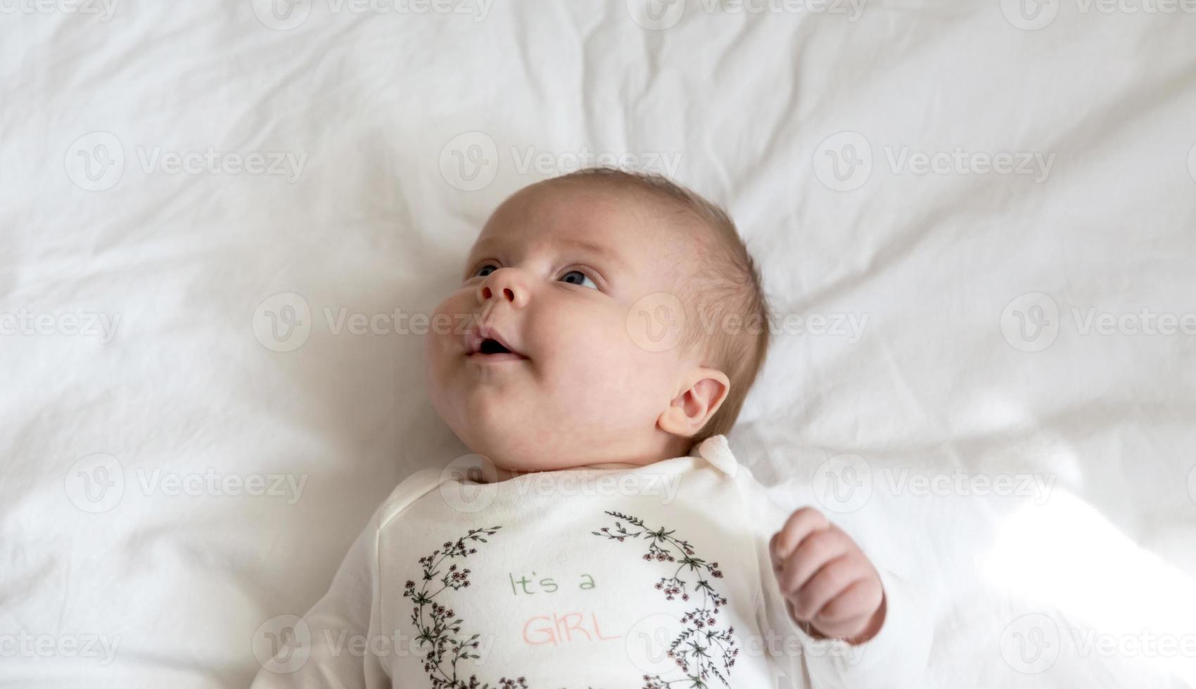 een close-up portret van een babymeisje dat in bed ligt en glimlacht foto